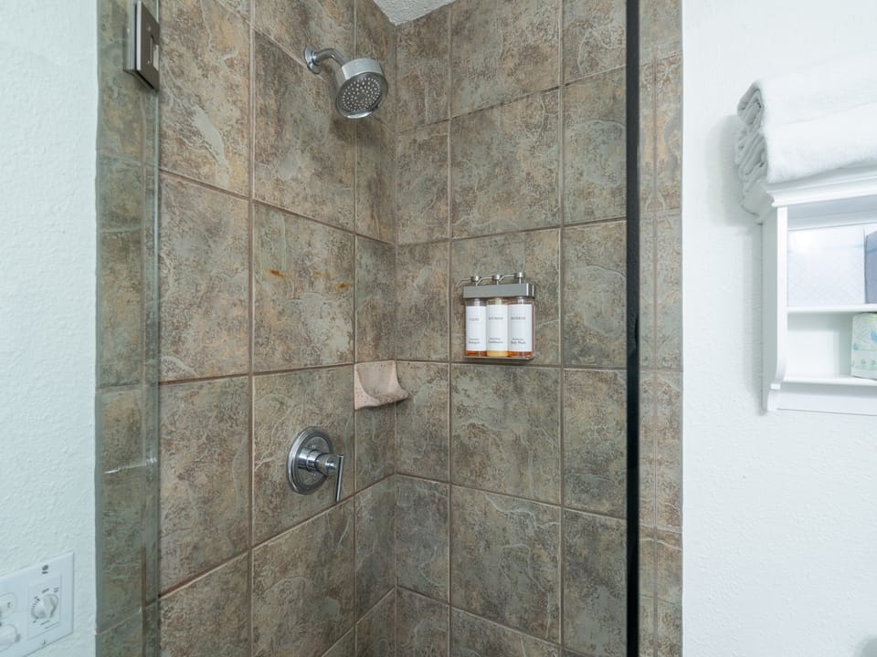 Step into a beautifully tiled walk-in shower with rainfall showerhead, built-in niche for your toiletries, and fresh towels ready for your arrival.