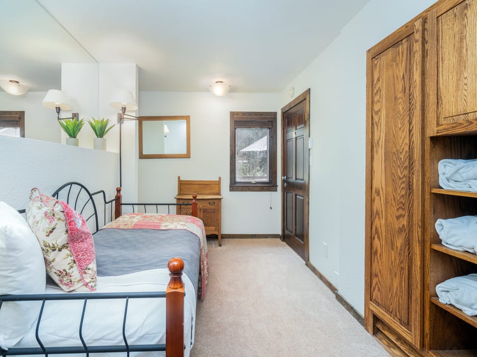 A peaceful bedroom awaits, featuring a cozy bed dressed with charming floral accents and plenty of space to unwind. Soft lighting and warm wood details create your own restful retreat.