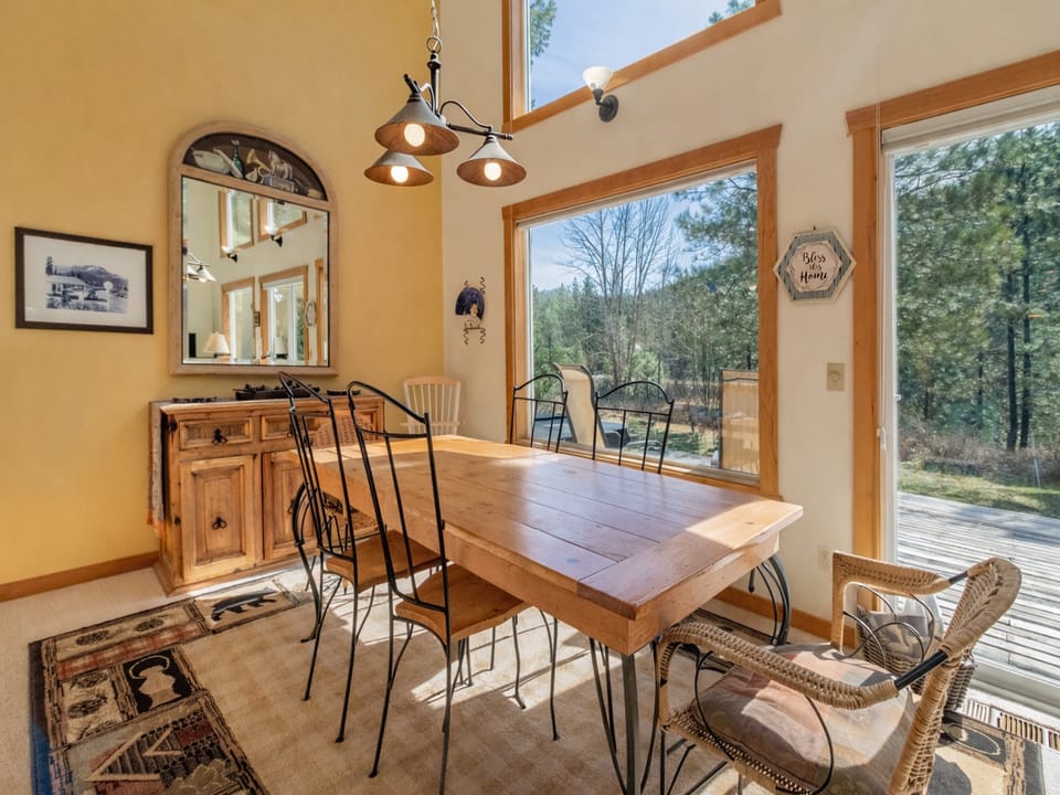 Gather around your rustic dining table where warm sunlight streams through floor-to-ceiling windows, creating the perfect spot for memorable meals.