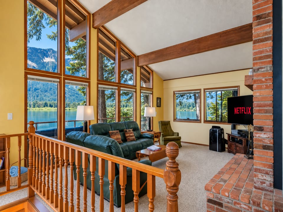 Classic brick fireplace, and comfortable furnishings create a cozy, nostalgic retreat. Large windows bring in the surrounding forest views, making this an inviting place to relax after a day on the lake (1)