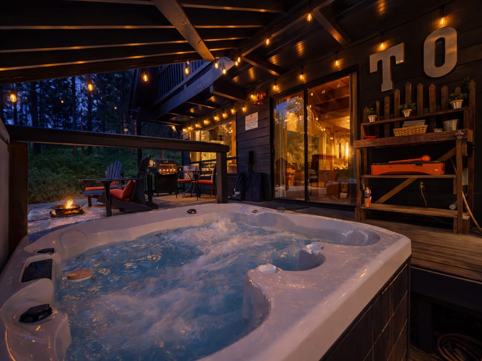 Soak in your private hot tub under twinkling string lights, with cozy fire pit seating nearby for the perfect evening retreat.