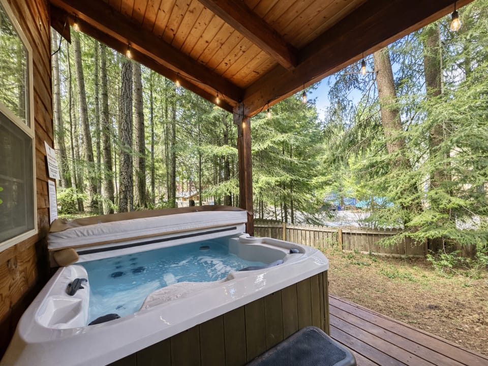 Unwind in your private hot tub sanctuary, surrounded by towering evergreens and forest tranquility on your covered deck.