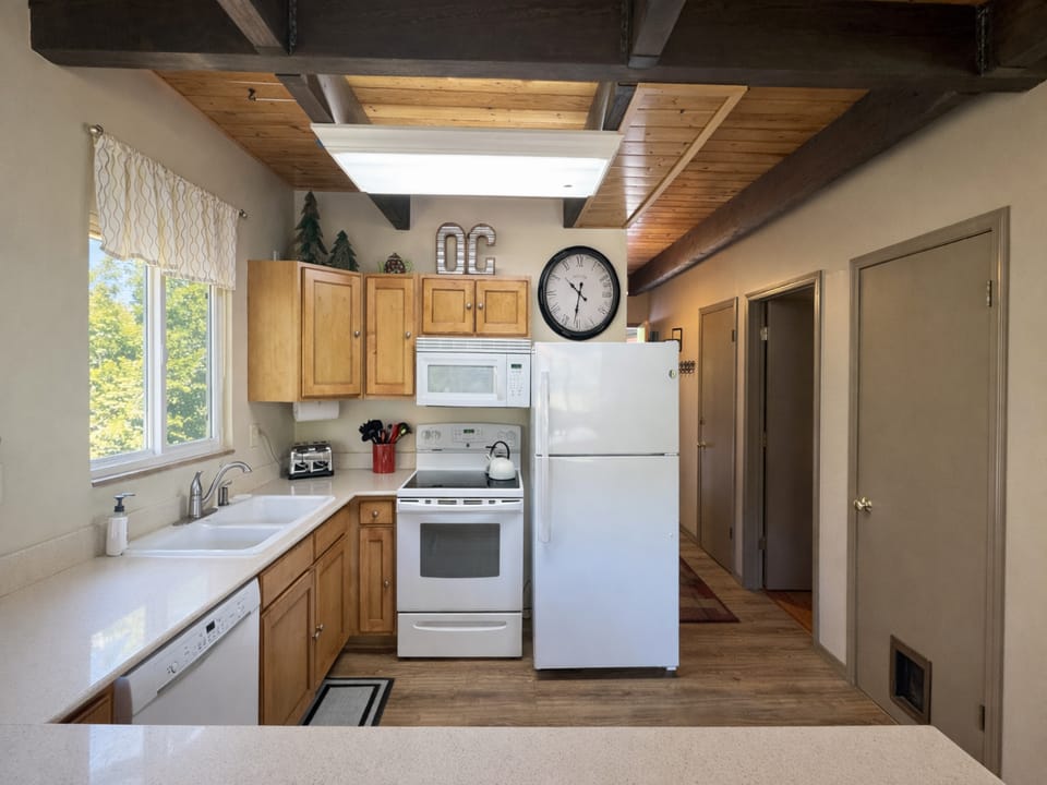 Your fully equipped kitchen invites home-cooked meals with warm wood cabinets, modern appliances, and charming exposed beam ceiling details.
