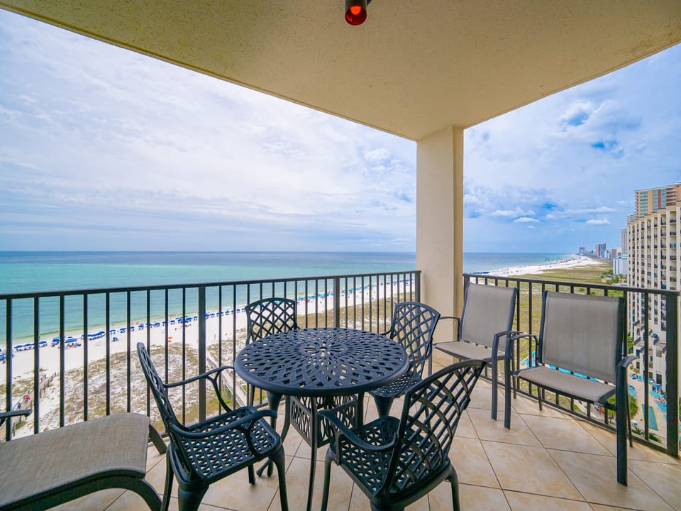 Stunning beachfront view showcases the tranquil beach, inviting pool area, and nearby resort buildings from the balcony