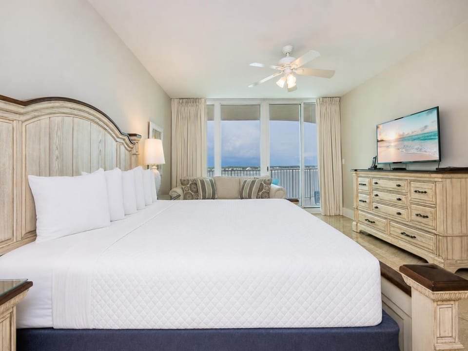 Spacious master bedroom featuring a king bed, elegant decor, additional twin bed, and a stunning view from the balcony