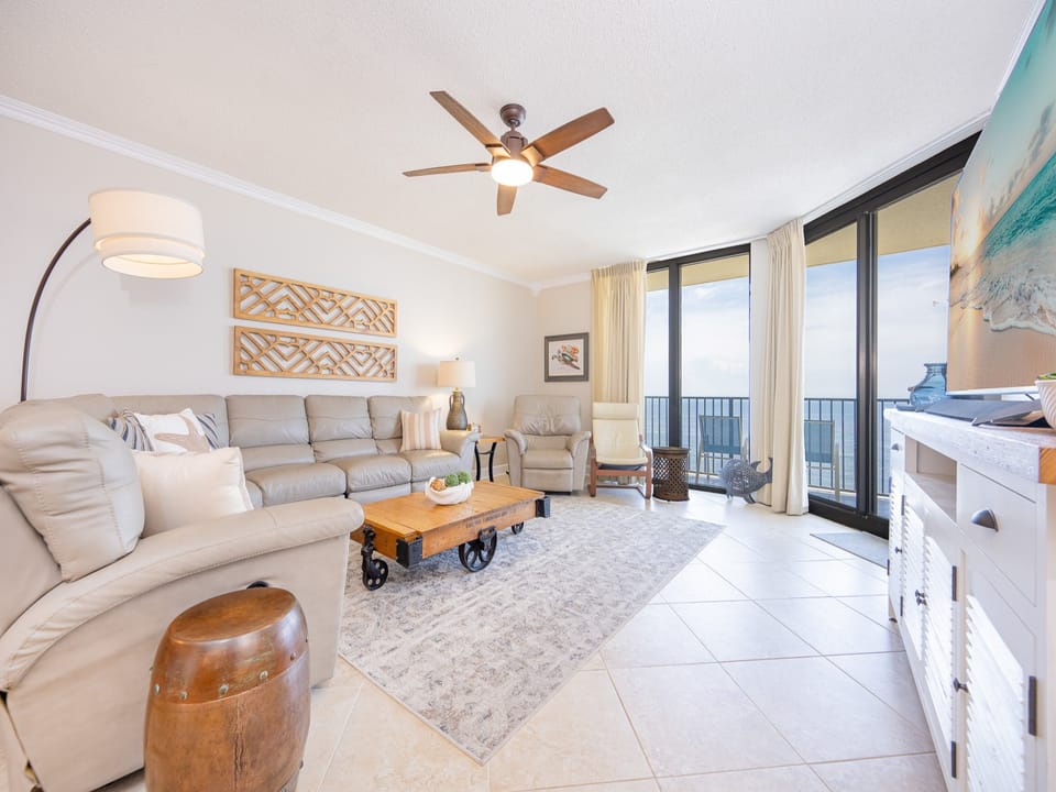Cozy living area features a plush sofa, wooden coffee table, and large windows showcasing a breathtaking beachfront view