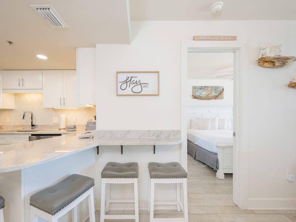 A sleek breakfast bar with gray stools complements the modern kitchen, featuring a marble countertop and stylish decor