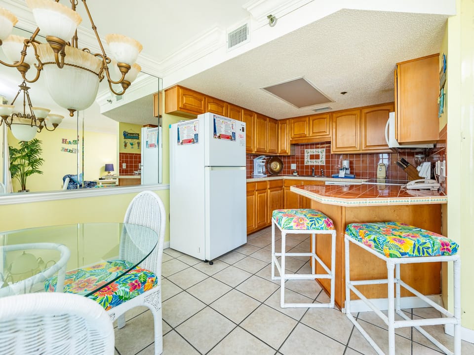 The kitchen features warm wooden cabinetry, a colorful tiled backsplash, and a convenient layout for meal preparation