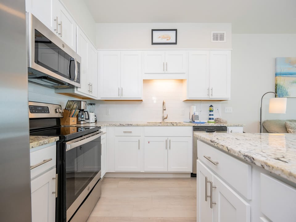 The kitchen features stainless appliances, granite countertops, a spacious island, and cozy seating area for casual dining