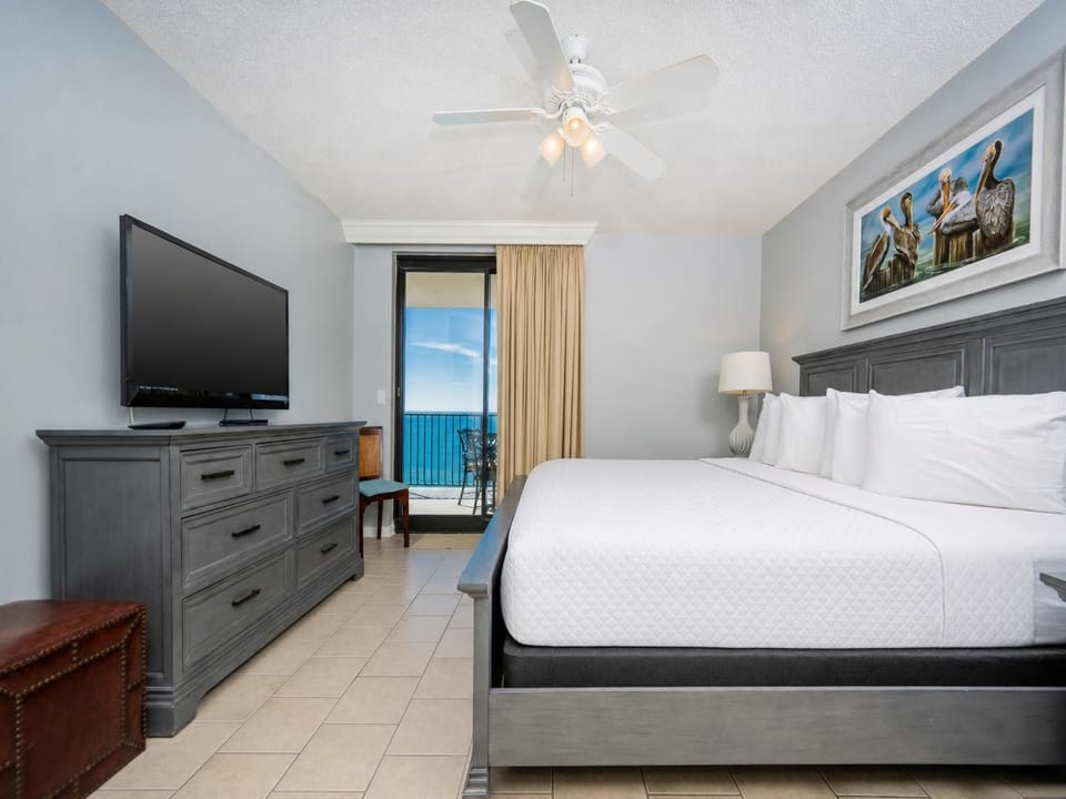 Relax in this inviting master bedroom featuring a king bed, flat-screen TV, and easy access to the balcony with beach views