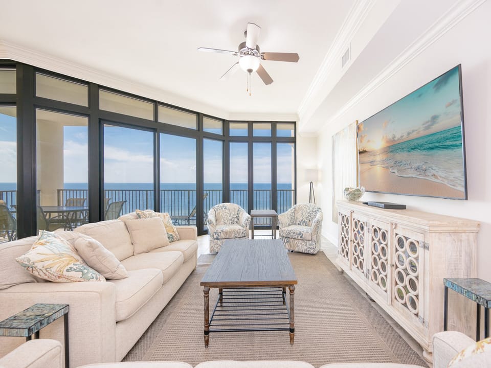 Bright and airy living room featuring plush seating, a large TV, and vibrant artwork for a cozy beachside retreat