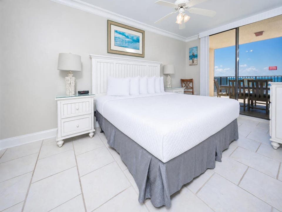 Bright master bedroom featuring a king bed, elegant white furnishings, and a sliding door to the extended balcony