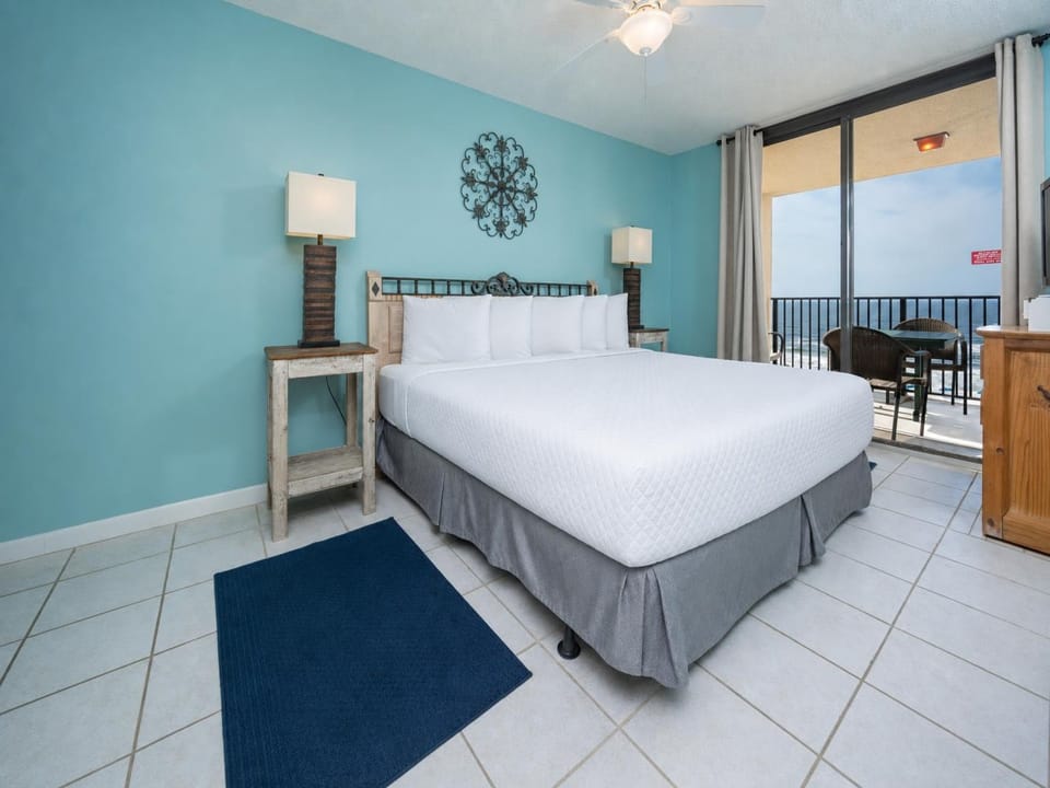 The master bedroom features a plush king bed, with a balcony view featuring outdoor seating overlooking the beach