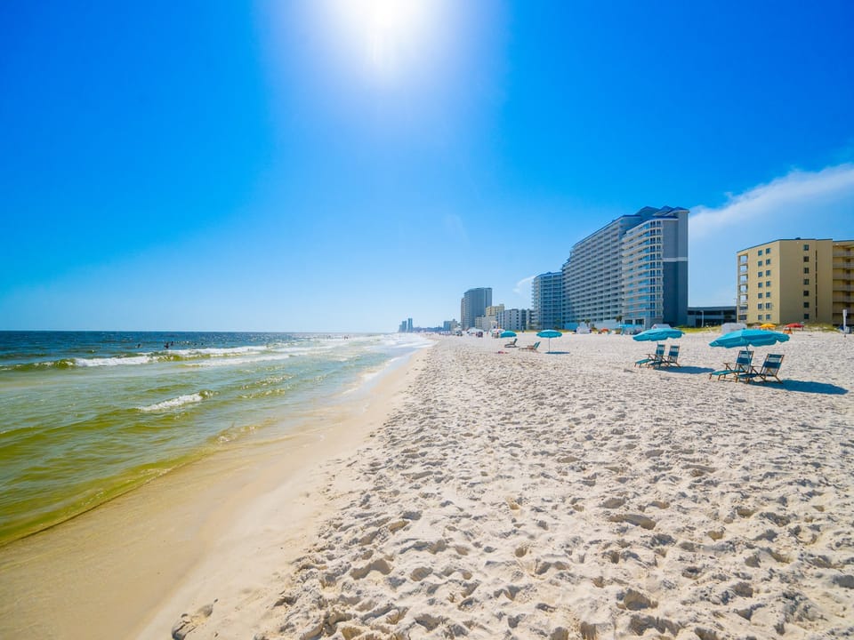 Experience the beautiful beachfront with soft sand, gentle waves, and vibrant beachgoers for a perfect day by the water