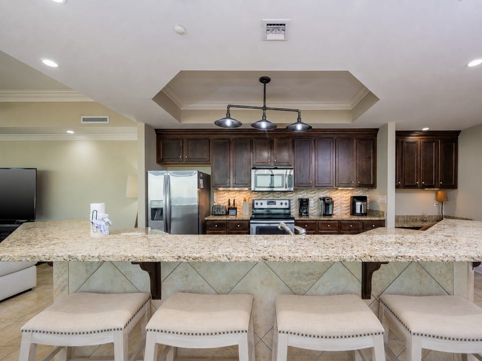 The kitchen features dark wood cabinets, stainless appliances, granite countertops, and a workspace with complimentary WiFi