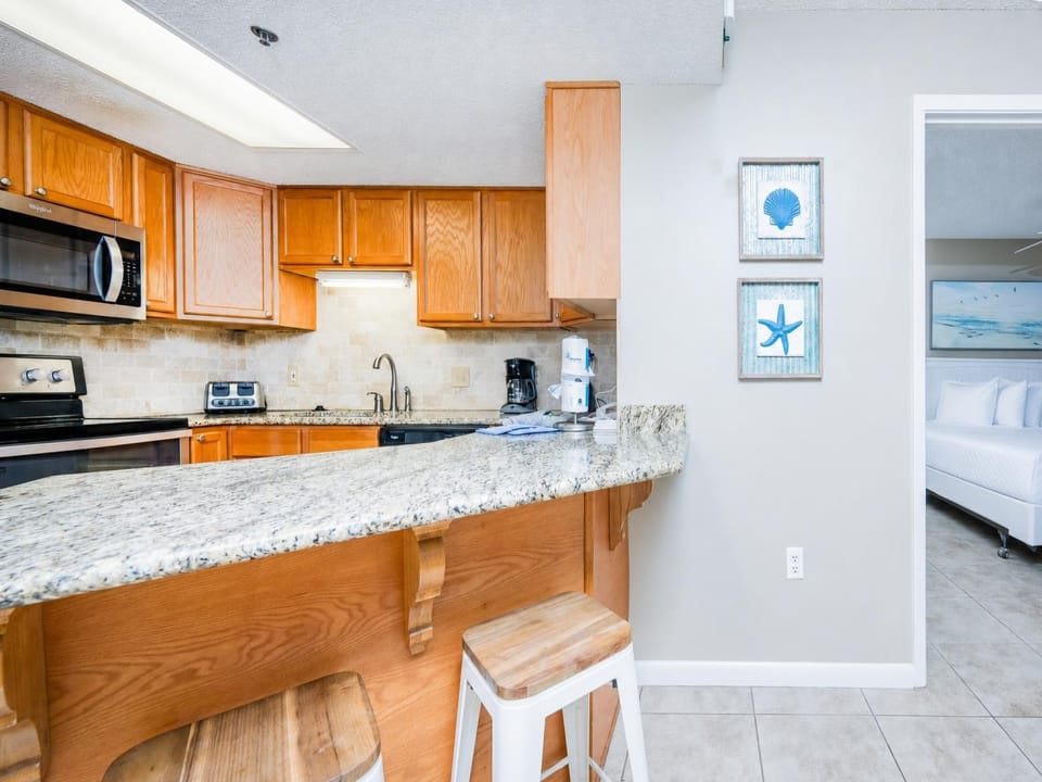 Modern kitchen area features warm wood cabinetry, a granite breakfast bar with seating, and a breakfast bar for convenience