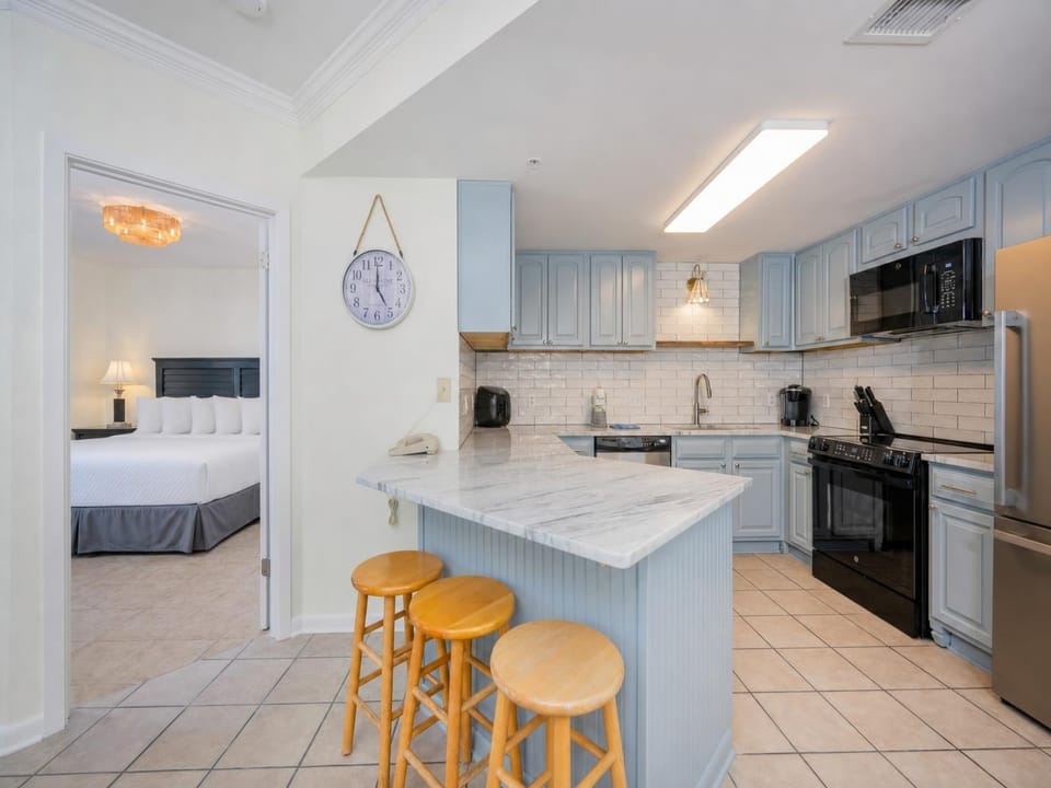 Bright kitchen with soft blue cabinets invites you to prepare meals while chatting with family nearby in the master suite
