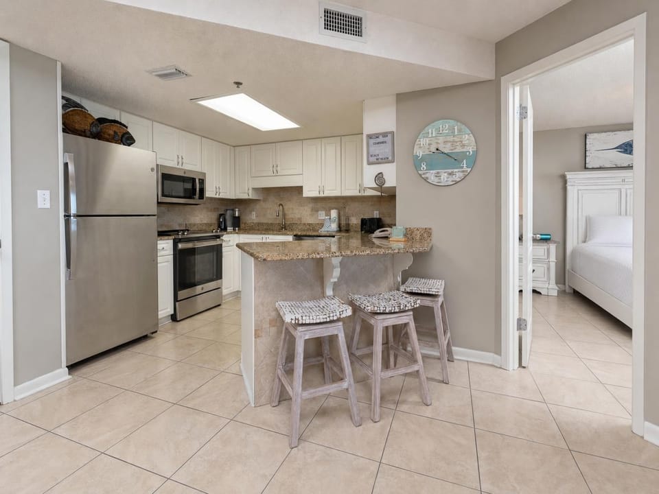 Bright kitchen area features granite countertops, stainless appliances, and a breakfast bar with seating