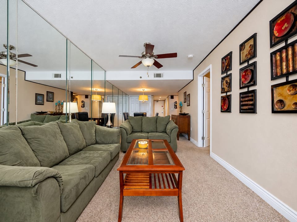 This living area features a comfortable green couch with a queen sleeper, a large TV, and a beautiful view of the beach