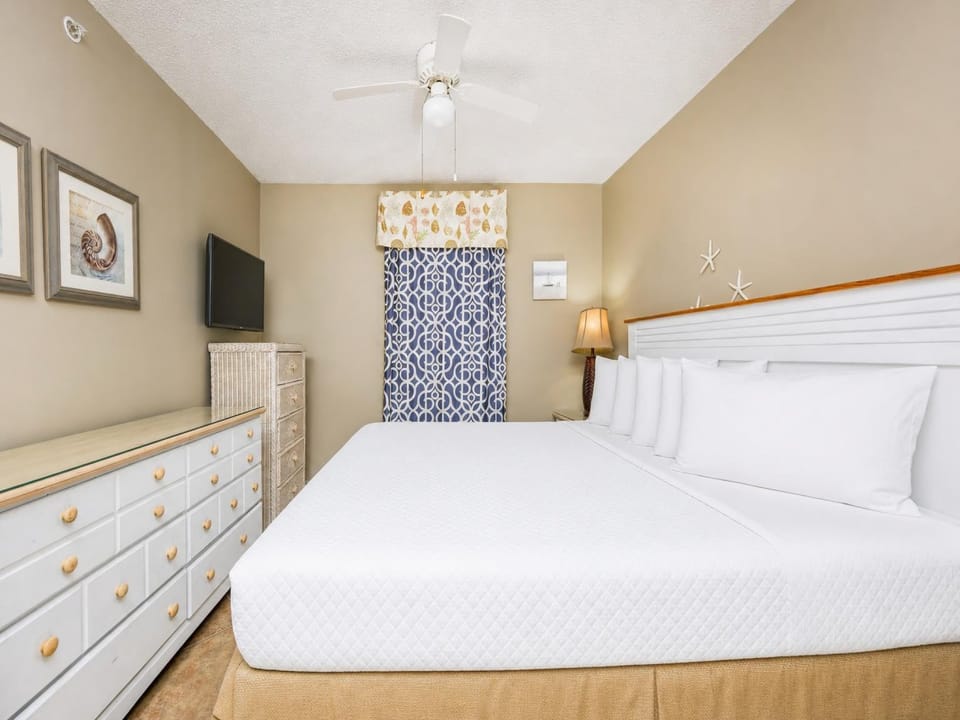 The master bedroom features a large bed, a mounted TV, and charming coastal decor, perfect for a relaxing getaway