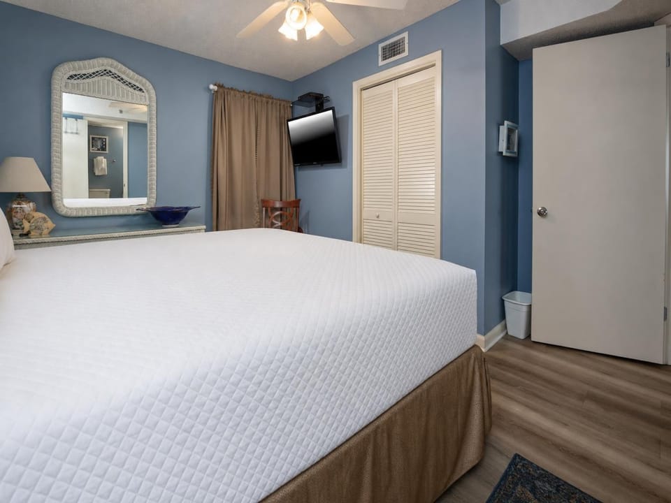 Bright blue walls complement the king bed, while a wall-mounted TV and tasteful decor enhance the inviting atmosphere