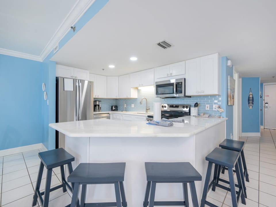 White cabinetry and marbled countertops in this inviting kitchen area with a breakfast bar and stainless appliances