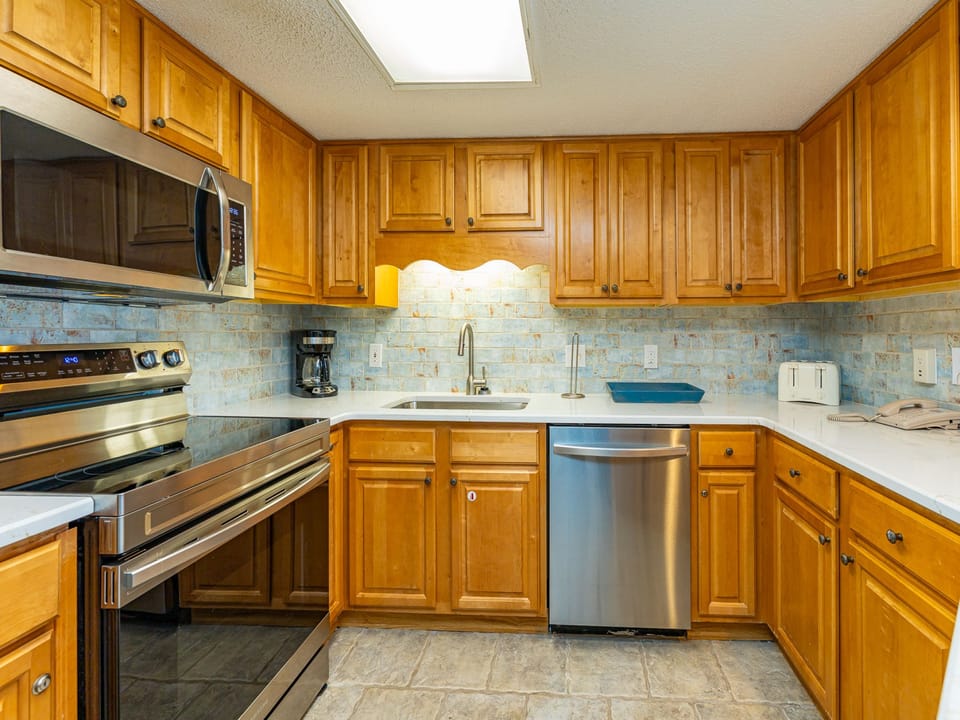 Warm wood cabinetry complements the modern appliances in this inviting kitchen, featuring ample counter space for meal prep