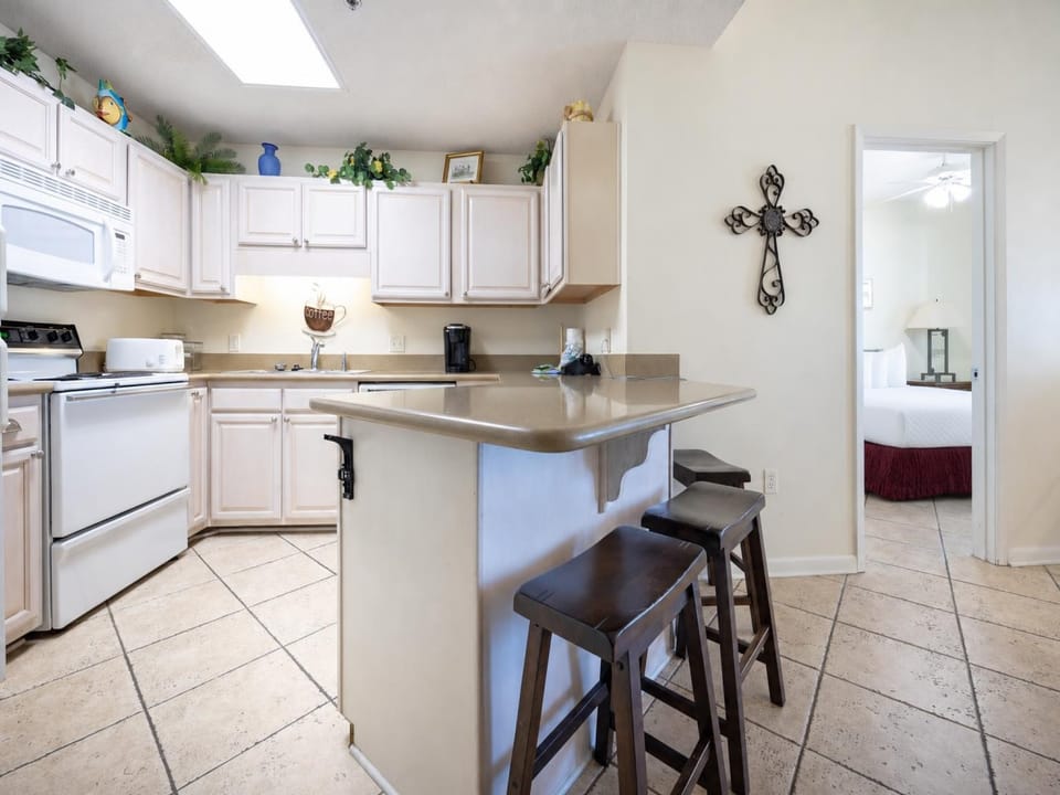 Bright kitchen area features light cabinetry, a breakfast bar with seating, and white appliances