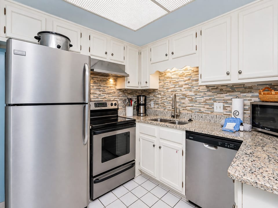 The kitchen features stainless appliances, granite countertops, coffee maker, and a stylish backsplash