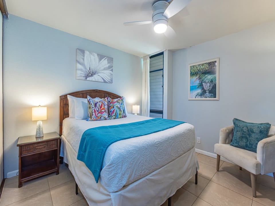 Unwind in this serene bedroom with coastal touches. Fresh linens, tropical art, and a ceiling fan create your perfect retreat after a day of island adventures.
