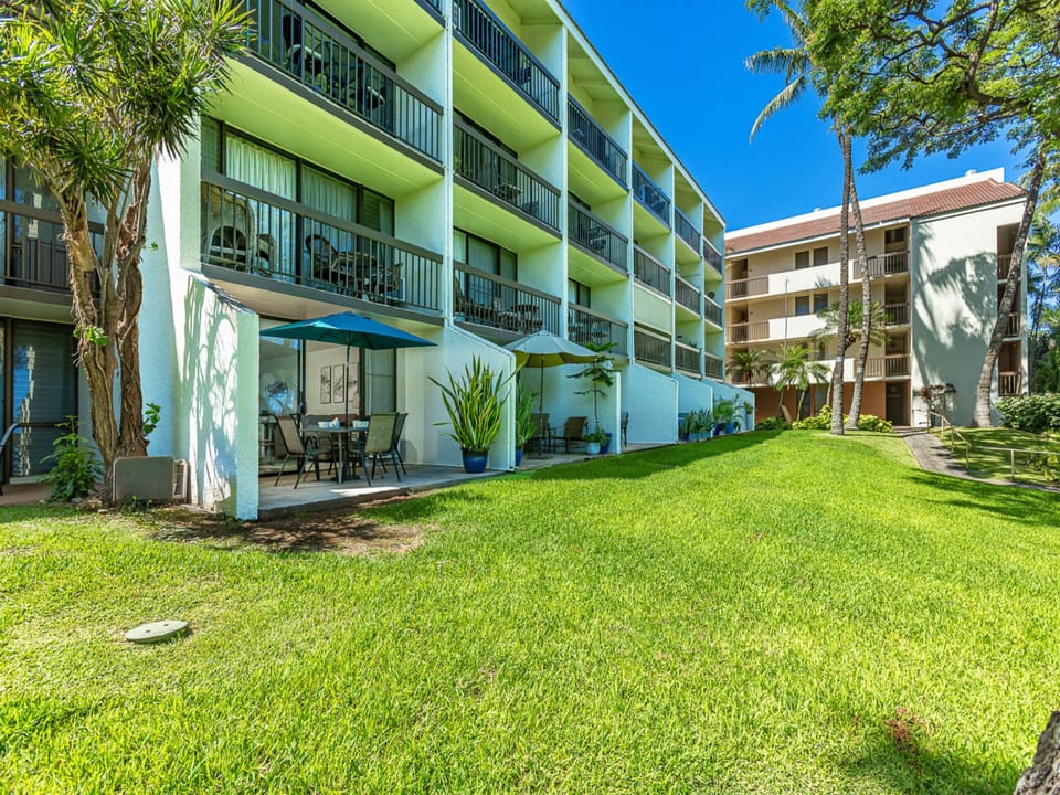 The property features tropical landscaping with palm trees and lush lawns. Multiple buildings with private balconies provide vacation rental accommodations in a sunny, resort-style setting.