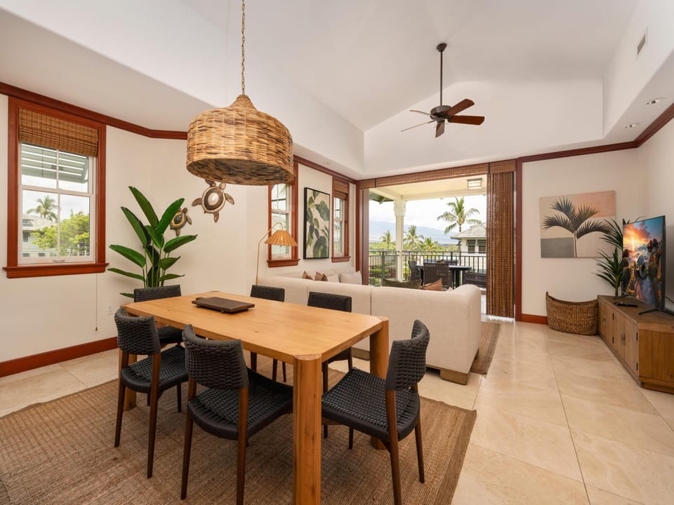 Gather around the handsome wood dining table beneath a tropical woven pendant, where ocean breezes drift through open doors and your group can share meals together with palm-lined views just beyond.