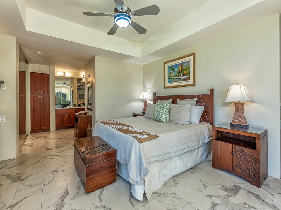 Picture yourself unwinding in your elegant bedroom, where rich wood furnishings and soft lighting create a serene island-inspired retreat. Coastal artwork and plush bedding await your arrival.