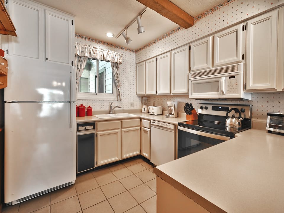 Kitchen includes tiled flooring, white countertops, cabinets and appliances.