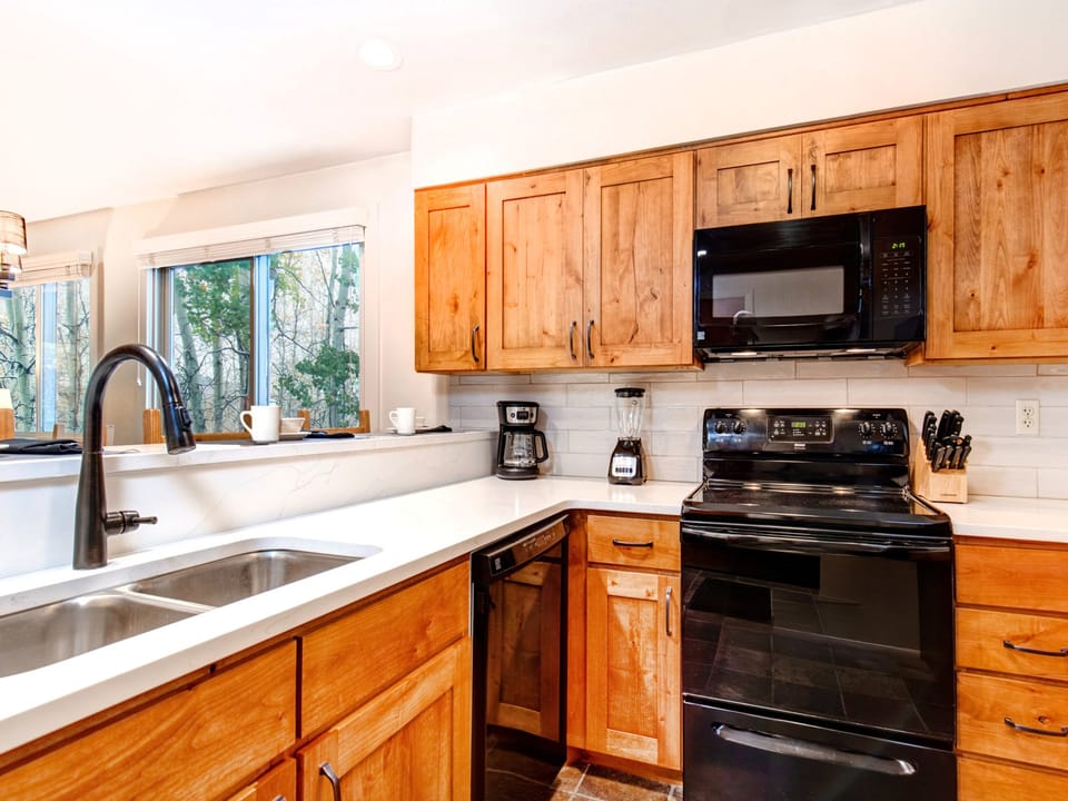 Snow Flower 150's well equipped kitchen with wood cabinets and black appliances.