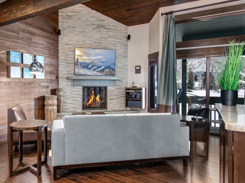 The open concept living room, dining and kitchen area with roaring fire and TV.