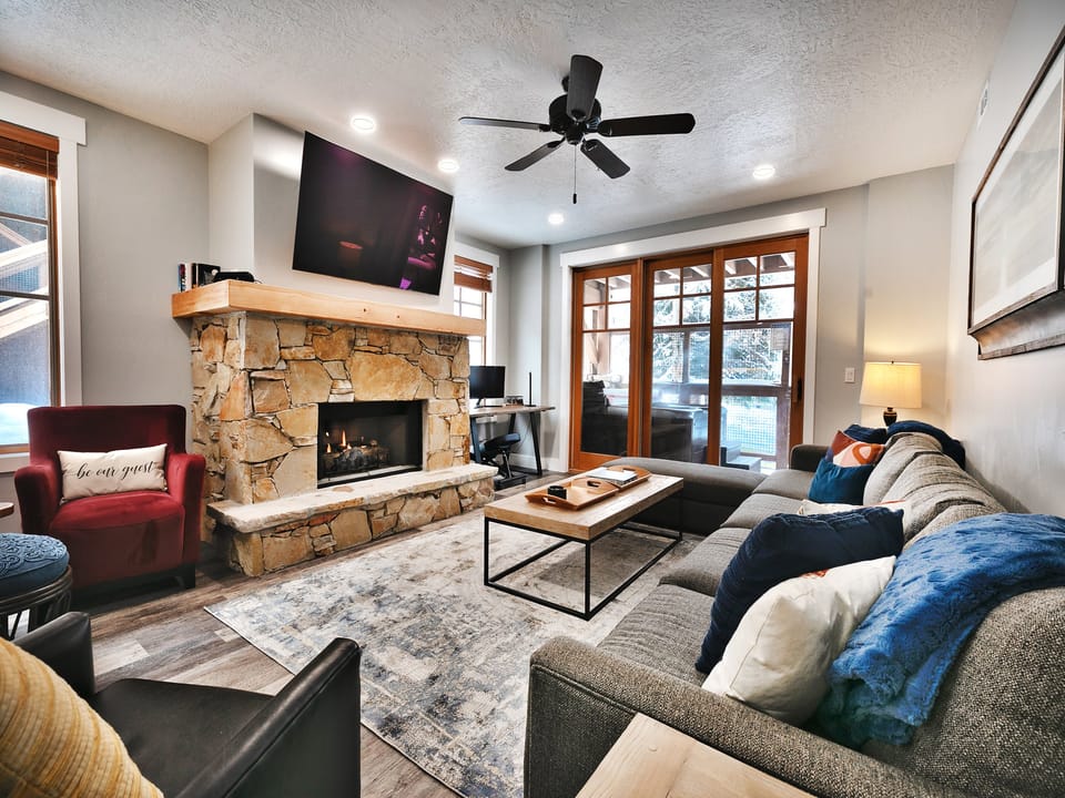 Hardwood floors in the living room with large area rug, flagstone hearth and wall mounted TV