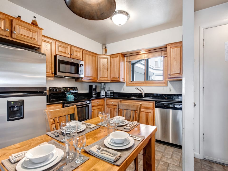 Snow Flower 65's kitchen with wood cabinets, stainless steel appliances, and a dining table with seating for 4 in the middle.