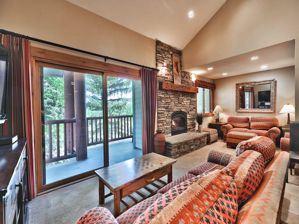 Living room features a beautiful rock gas fireplace and access to the private patio
