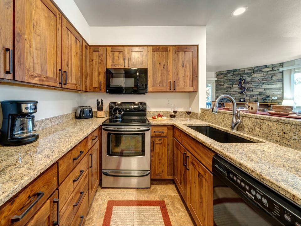 Kitchen includes granite countertops, wood cabinets, stainless steel oven and black appliances.
