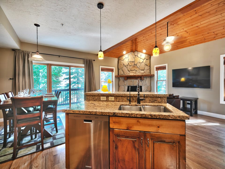 Two-tiered kitchen island with granite countertops, wooden cabinets and stainless steel dishwasher