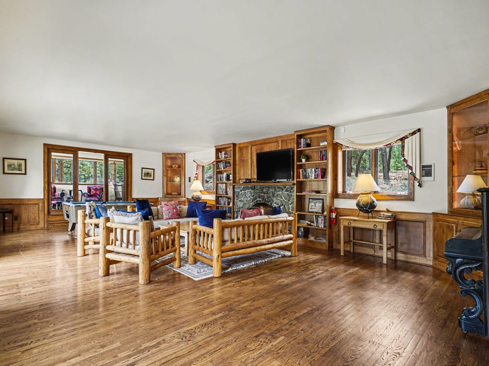 Gather around the stone fireplace in this spacious living room with rich wood floors, built-in shelving, and cozy seating perfect for relaxing.