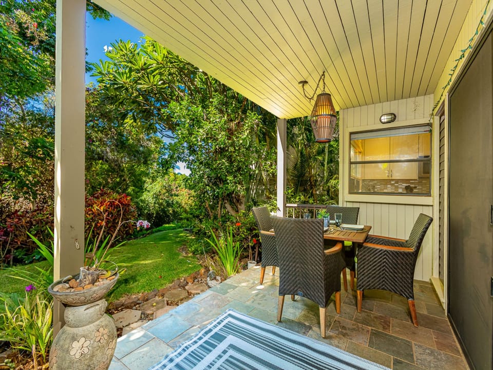 Covered lanai with lighting surrounded by exotic landscape.