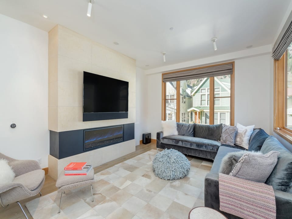 Ironwood A - a stunning, navy L shaped velvet sofa surrounds a flat screen TV and gas fireplace.