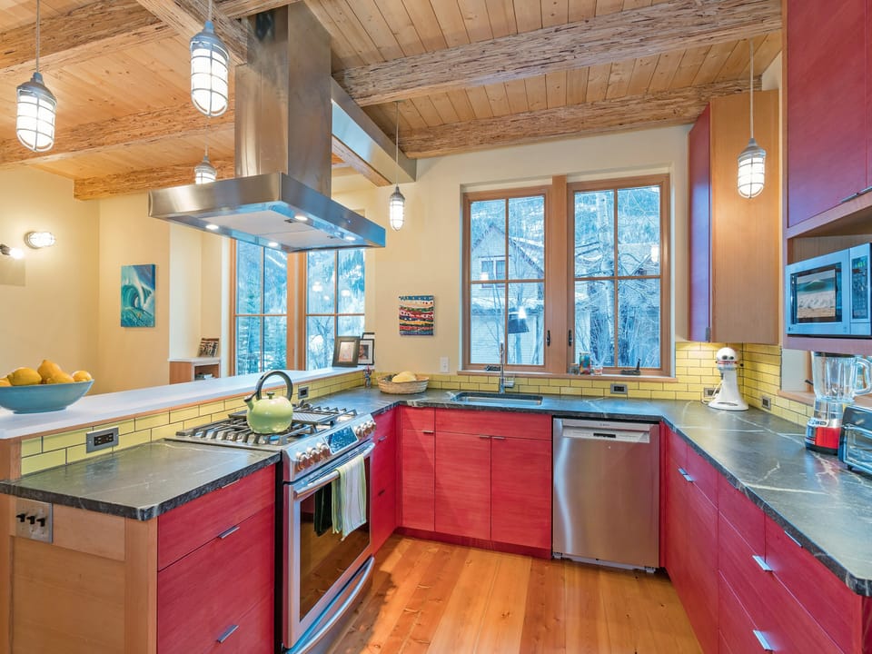 Stainless appliances include oven, dishwasher, and microwave. The red cabinetry creates a warm, contemporary kitchen.