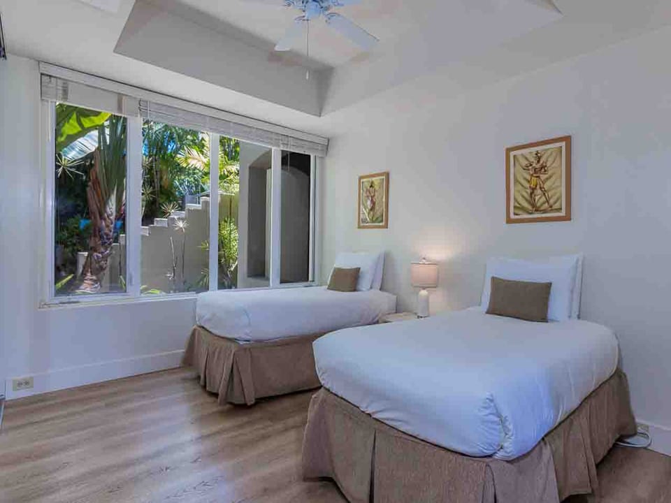 Drift off in crisp white linens while tropical breezes filter through sliding glass doors that frame lush greenery just beyond your private retreat.