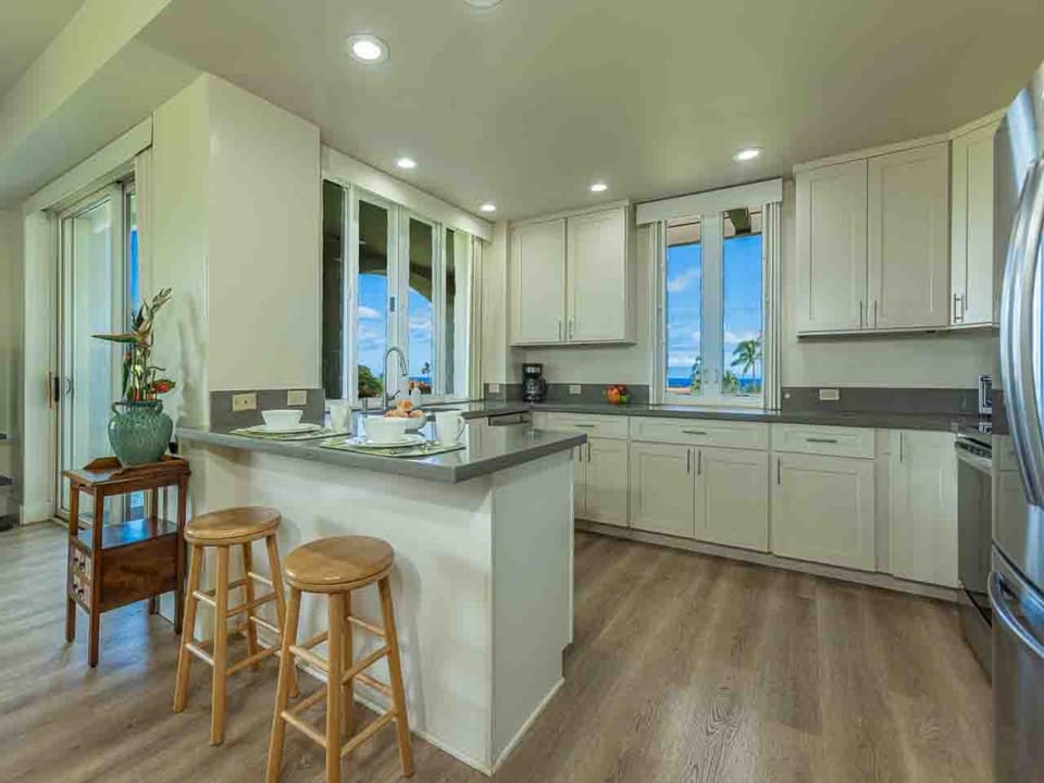 Your fully equipped kitchen features modern appliances and a breakfast bar with seating—perfect for preparing meals while enjoying stunning ocean views through the large windows.