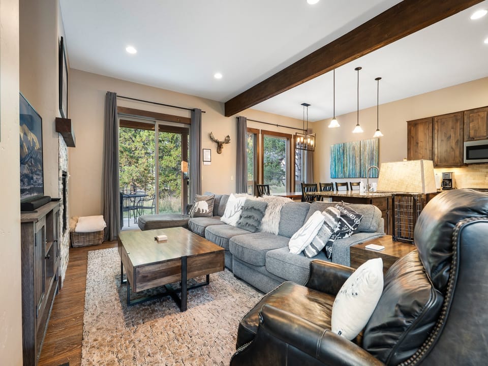 - Spacious living area with sectional seating and wood beams opens to a forest view patio - Cozy fireplace and lodge style touches make it ideal for relaxing after mountain fun - Connects seamlessly to the dining and kitchen spaces