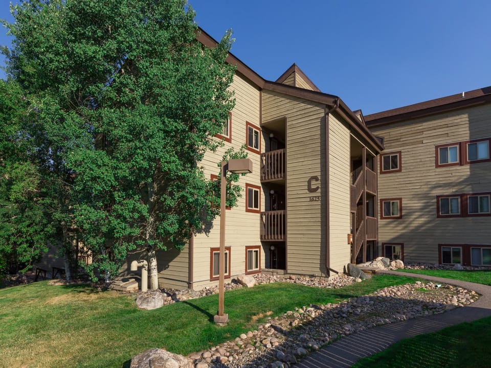 Outside view of Building - Three story, beige building with tall aspens alongside.