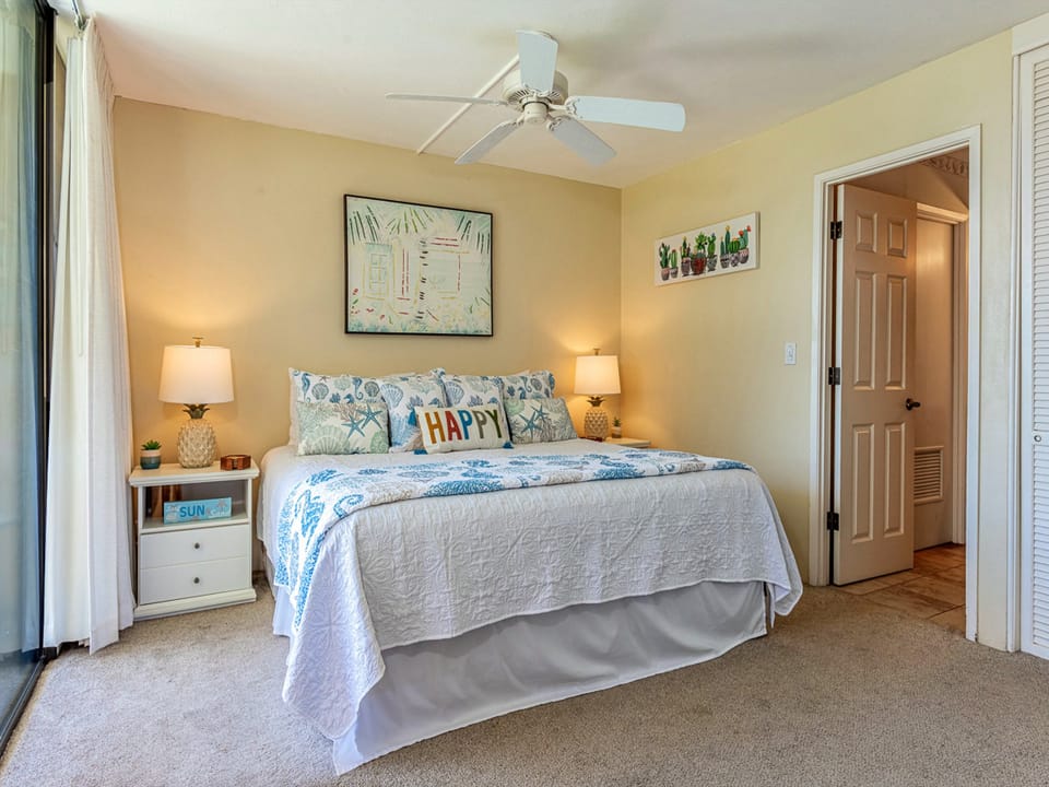 Your bright, welcoming bedroom features a plush bed with cheerful coastal décor, soft lighting, and a ceiling fan for comfort. Relax in this serene retreat after a day exploring.